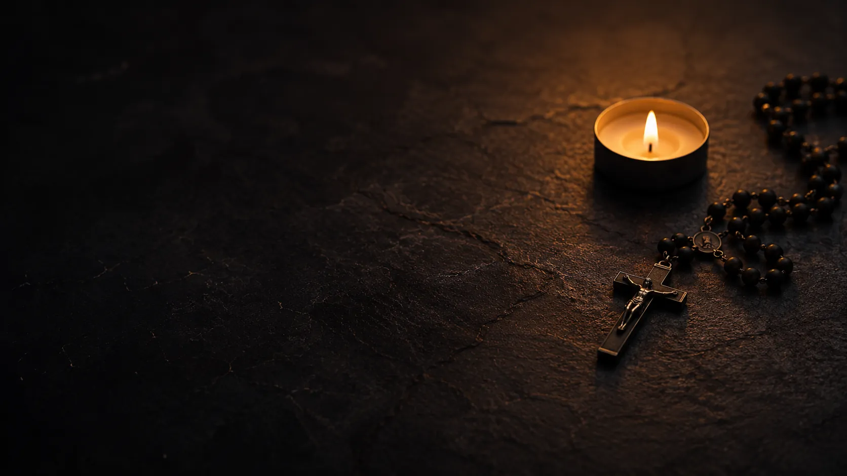 A candle, rosary, and crucifix on a dark stone surface, symbolizing Catholic prayer during anxiety.